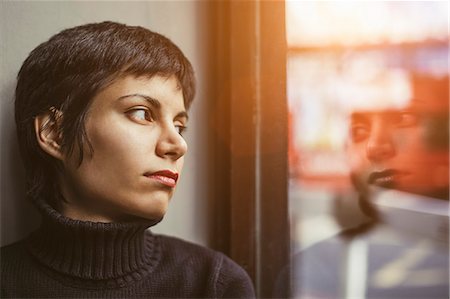 Portrait of young woman gazing out of window at the street Stock Photo - Premium Royalty-Free, Code: 649-07803222