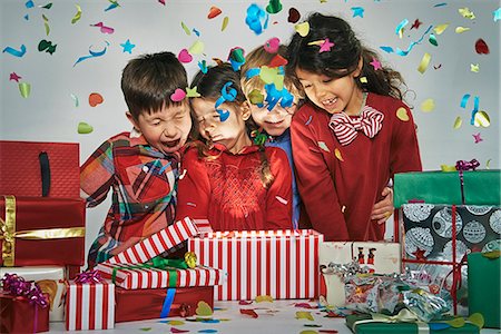 Surprised brothers and sisters unwrapping glowing christmas gift box with exploding confetti Stock Photo - Premium Royalty-Free, Code: 649-07803309