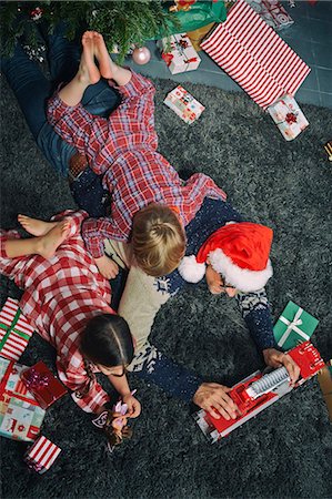 simsearch:6122-07696599,k - Father lying on sitting room floor opening christmas gifts with daughter and son Photographie de stock - Premium Libres de Droits, Code: 649-07803313