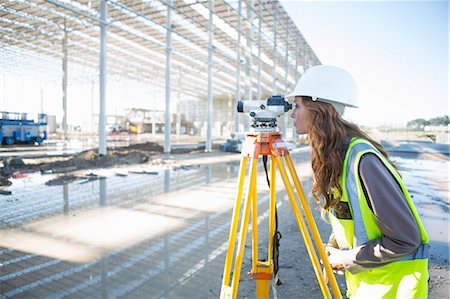 Surveyor leaning forward to look through level on construction site Stock Photo - Premium Royalty-Free, Code: 649-07803331