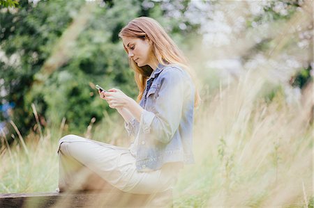 simsearch:649-07804672,k - Young woman reading texts on smartphone on park bench Stockbilder - Premium RF Lizenzfrei, Bildnummer: 649-07803346