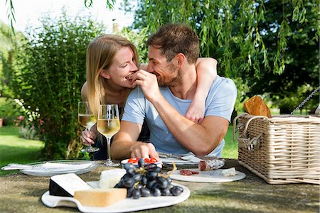 Mid adult man feeding girlfriend from picnic table in garden Photographie de stock - Premium Libres de Droits, Code: 649-07803439