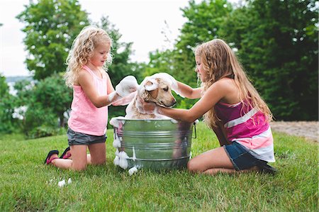 Two sisters bathing pet Labrador Retriever puppy Stock Photo - Premium Royalty-Free, Code: 649-07803500