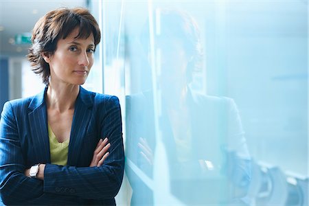 Portrait of mature businesswoman leaning against glass wall with arms crossed Foto de stock - Sin royalties Premium, Código: 649-07803576