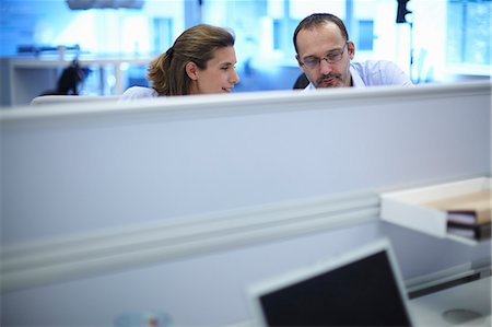 simsearch:649-07736470,k - Businessman and businesswoman chatting at their desks in office Stock Photo - Premium Royalty-Free, Code: 649-07803599