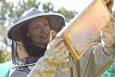 Female beekeepers holding up honeycomb tray on city allotment Stock Photo - Premium Royalty-Free, Code: 649-07803953