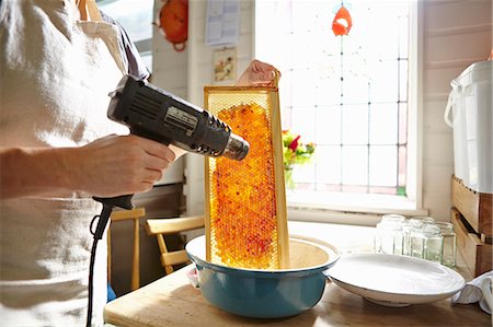 Female beekeeper in kitchen melting wax on frame of honey Stock Photo - Premium Royalty-Free, Code: 649-07803961