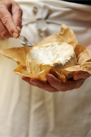 Man holding goats cheese and cheese knife, focus on hands Stock Photo - Premium Royalty-Free, Code: 649-07905135