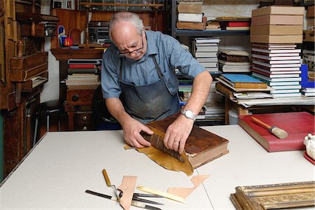 simsearch:649-07905311,k - Senior man repairing antique book spine in traditional bookbinding workshop Stock Photo - Premium Royalty-Free, Code: 649-07905309