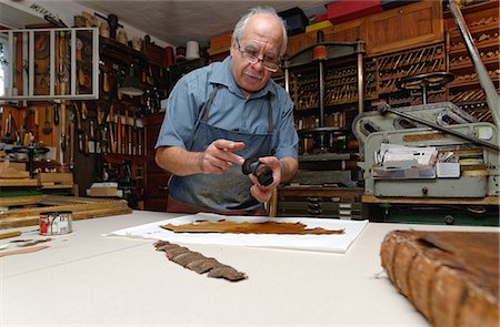 Senior man repairing fragile book spine in traditional bookbinding workshop Photographie de stock - Premium Libres de Droits, Code: 649-07905310