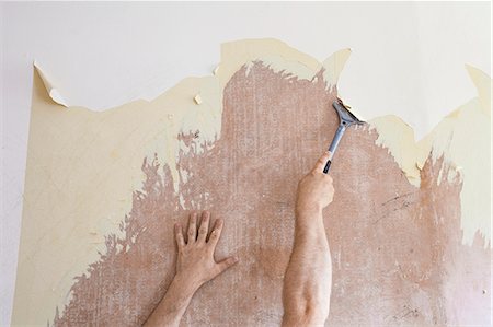 Mature man using scraper to scrape off old wallpaper Photographie de stock - Premium Libres de Droits, Code: 649-07905436