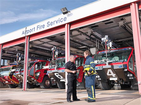 encouragement - Officer and fireman in front of fire engines in airport fire station Stock Photo - Premium Royalty-Free, Code: 649-07905575