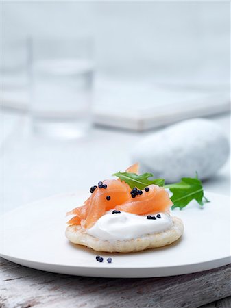 saveur - Smoked salmon and cream cheese blinis on wafer biscuit with caviar and rocket leaves garnish Photographie de stock - Premium Libres de Droits, Code: 649-07905606