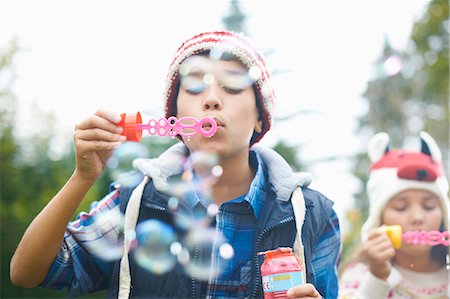 simsearch:614-09253603,k - Siblings blowing bubbles in garden Photographie de stock - Premium Libres de Droits, Code: 649-08004035