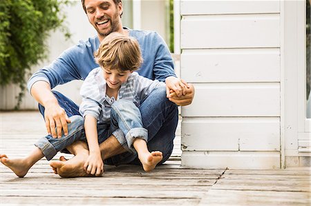 sitting on floor - Mid adult man and son laughing and tickling feet on porch Stock Photo - Premium Royalty-Free, Code: 649-08004069