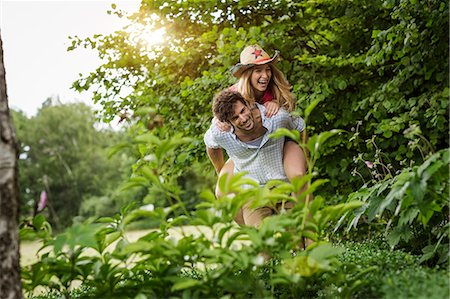 piggyback ride in the garden - Young man giving girlfriend a piggy back in garden Stock Photo - Premium Royalty-Free, Code: 649-08004080