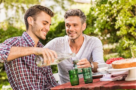 Two male friends having drink together at table in garden Stock Photo - Premium Royalty-Free, Code: 649-08004178