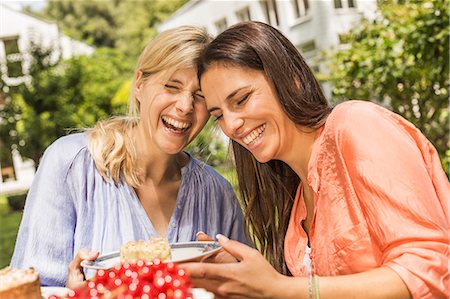 Two female friends in garden, laughing, holding plate with dessert Stock Photo - Premium Royalty-Free, Code: 649-08004191