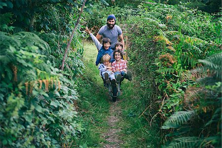 simsearch:649-07596306,k - Mid adult man pushing wheelbarrow full of boys in garden Photographie de stock - Premium Libres de Droits, Code: 649-08004287