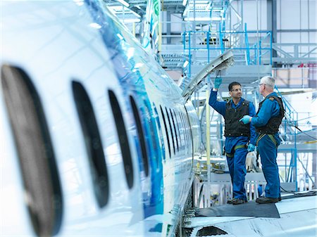 factory men - Engineers in discussion on  aircraft wing in aircraft maintenance factory Stock Photo - Premium Royalty-Free, Code: 649-08060082