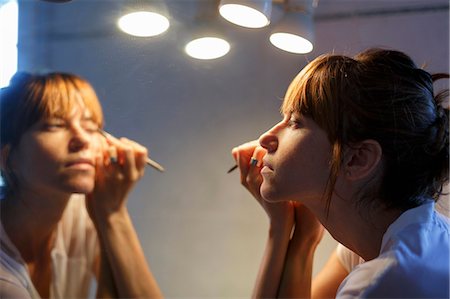 eyeliner - Mid adult woman applying eyeliner in bathroom mirror Foto de stock - Sin royalties Premium, Código: 649-08060166