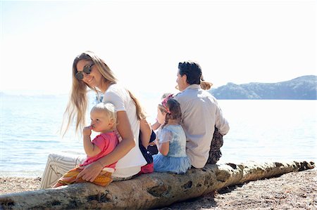 Family and friends sitting on tree trunk at beach, New Zealand Stock Photo - Premium Royalty-Free, Code: 649-08060160