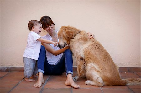 family with one child - Mid adult woman with baby daughter petting dog in kitchen Stock Photo - Premium Royalty-Free, Code: 649-08060171