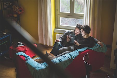 family inside a home - Couple sitting on sofa, looking at digital tablet Foto de stock - Sin royalties Premium, Código: 649-08060303
