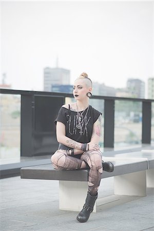 simsearch:649-08060330,k - Portrait of young female tattooed punk sitting rooftop wall Foto de stock - Royalty Free Premium, Número: 649-08060327