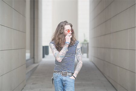 simsearch:649-08060336,k - Young male hippy smoking cigarette in city alley Stock Photo - Premium Royalty-Free, Code: 649-08060336