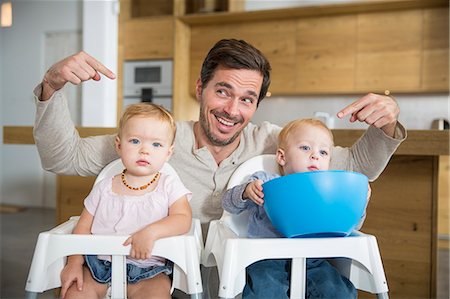 Father pointing at male and female twin toddlers in high chairs Photographie de stock - Premium Libres de Droits, Code: 649-08060399