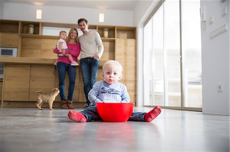 Family watching male toddler with bowl on dining room floor Foto de stock - Sin royalties Premium, Código: 649-08060402