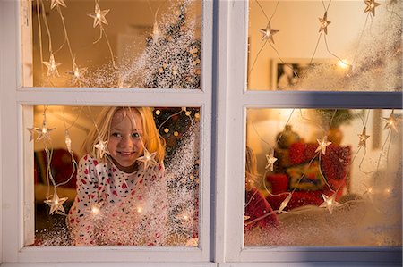 people light happy - Girl looking out of window with Christmas decorations Stock Photo - Premium Royalty-Free, Code: 649-08060448