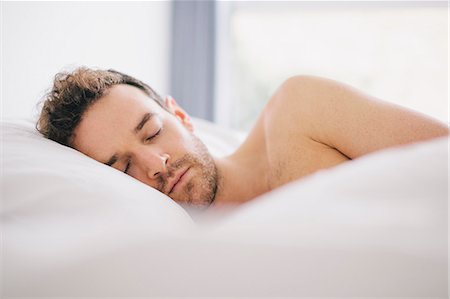 Young man lying on side asleep in bed Fotografie stock - Premium Royalty-Free, Codice: 649-08060604