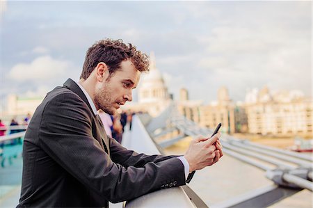 simsearch:649-07560148,k - Businessman reading smartphone texts whilst leaning on millennium bridge, London, UK Photographie de stock - Premium Libres de Droits, Code: 649-08060610