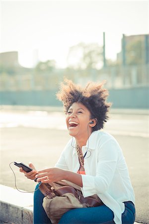 simsearch:649-08060771,k - Young woman laughing and listening to smartphone music in city parking lot Photographie de stock - Premium Libres de Droits, Code: 649-08060775