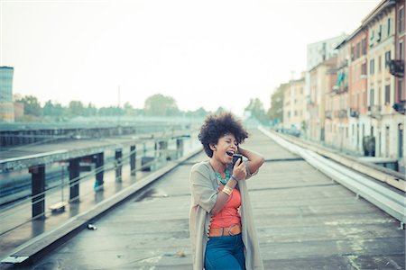 singing - Young woman singing to music from smartphone in city industrial area Stock Photo - Premium Royalty-Free, Code: 649-08060798