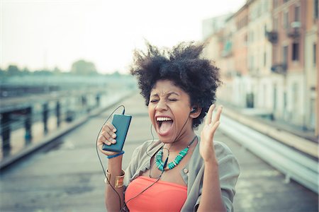 exciting women - Young woman screaming to music from smartphone in city industrial area Stock Photo - Premium Royalty-Free, Code: 649-08060799