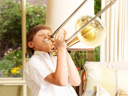 proud - Boy practicing trombone in sitting room Foto de stock - Sin royalties Premium, Código: 649-08060816