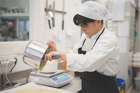 Baker pouring mixture onto tray in kitchen Photographie de stock - Premium Libres de Droits, Code: 649-08084570