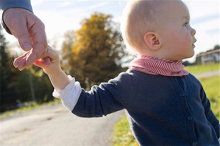 simsearch:649-07520975,k - Baby girl toddling on rural road holding fathers hand Foto de stock - Sin royalties Premium, Código: 649-08084692