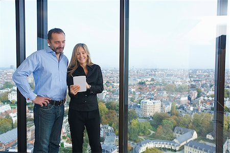 Businessman and woman using digital tablet in front of office window with Brussels cityscape, Belgium Photographie de stock - Premium Libres de Droits, Code: 649-08084738