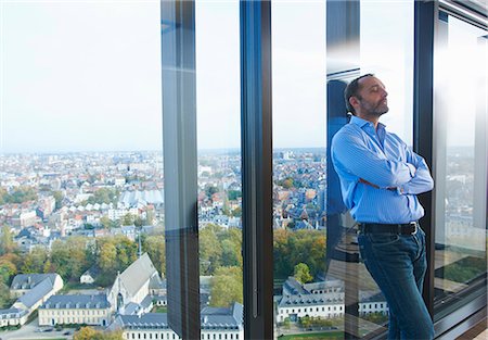 Worried businessman leaning against office window with Brussels cityscape, Belgium Stock Photo - Premium Royalty-Free, Code: 649-08084749