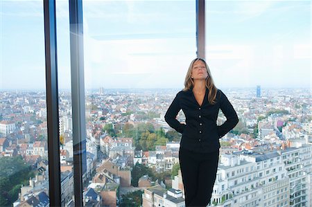 Tired businesswoman in front of office window with Brussels cityscape, Belgium Stock Photo - Premium Royalty-Free, Code: 649-08084740
