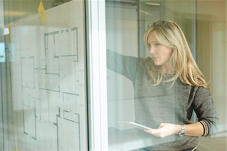 Architect looking at plans taped to glass wall Photographie de stock - Premium Libres de Droits, Code: 649-08084761