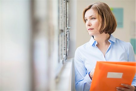 simsearch:649-08950729,k - Mature businesswoman with file gazing out of office window Stock Photo - Premium Royalty-Free, Code: 649-08084890