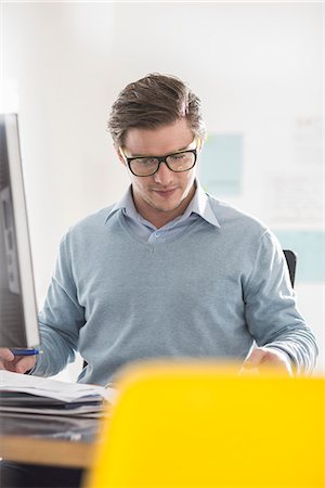 electronic devices for communication - Young businessman doing paperwork at office desk Stock Photo - Premium Royalty-Free, Code: 649-08084909