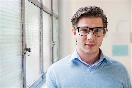 Portrait of young businessman next to office window Stock Photo - Premium Royalty-Free, Code: 649-08084901