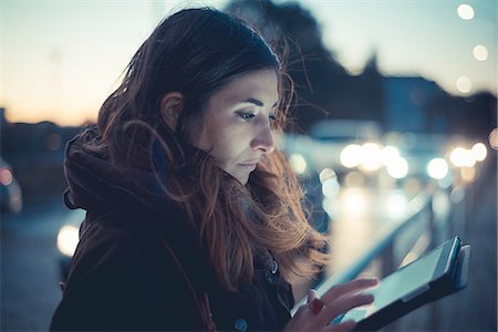 evening - Mid adult woman using digital tablet touchscreen on street at dusk Stock Photo - Premium Royalty-Free, Code: 649-08084946
