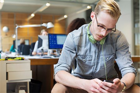 Young man choosing music from smartphone in office Foto de stock - Sin royalties Premium, Código: 649-08084984